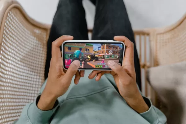 um par de mãos segurando um telefone tocando Fortnite com um gatilho magnético conectado ao telefone